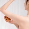 Une femme masse son bras gauche avec le masseur corporel à 7 billes.