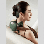 Une femme assise sur son canapé utilisant un masseur cervical et épaules SiaaSoo™ sur sa nuque pour relaxation.