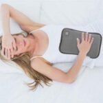 Femme allongée tenant la bouillotte peluche CuddleHeat™ sur son ventre pour apaiser les douleurs