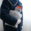 Bouillotte USB tenue dans les mains pour montrer sa taille et sa douceur.
