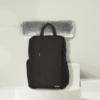 Coussin chauffant USB gris roulé et fixé sur un sac à dos pour un usage nomade.
