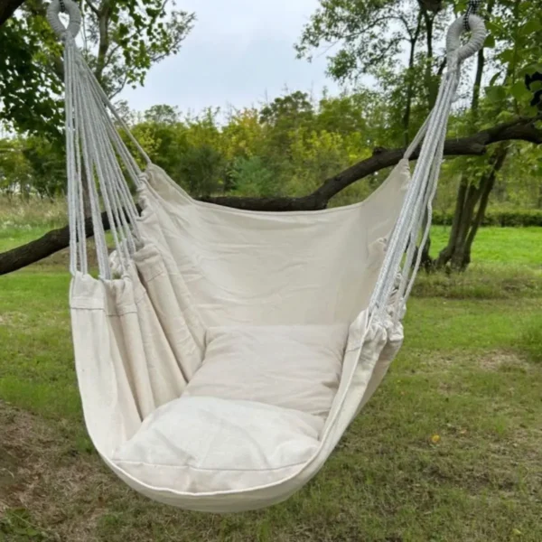 Chaise hamac suspendue crème avec coussin, accrochée à une branche en extérieur