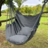 Chaise hamac suspendue grise avec coussin, installée en extérieur sous un arbre